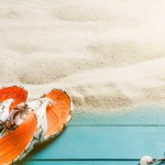 Holzplanken und Sandstrand mit Urlaubsutensilien